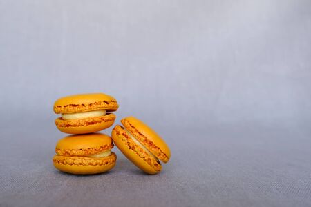 Stack of fresh tasty orange macarons sandwich cookies on gray background. Copy space. French confectionery.の写真素材