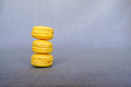 Pile of fresh delicious yellow lemon macarons on grey background. French pastry, sweet food. Copy...