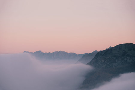 Mountain peaks covered with clouds during sunset. Alpine highlands landscape. Space for text