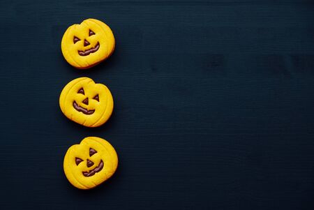 Funny Halloween jack o lantern cookies on black wooden background.の写真素材