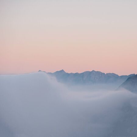 Mountain peaks covered with clouds during sunset. Alpine highlands landscape. Copy space.の写真素材