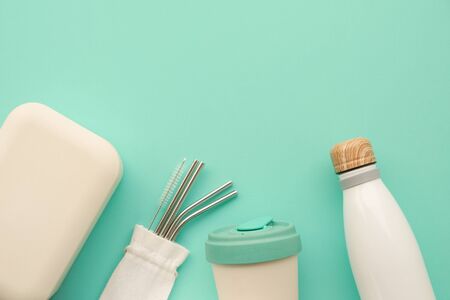 Reusable sustainable bamboo lunch box, coffee cup, metal straws, water bottle on mint background.の写真素材