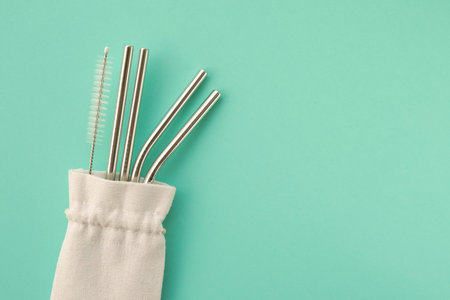 Reusable stylish eco friendly sustainable stainless steel metal straws on light blue background.