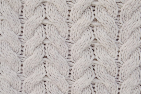 Beautiful beige knitted texture for background. White winter backdrop.