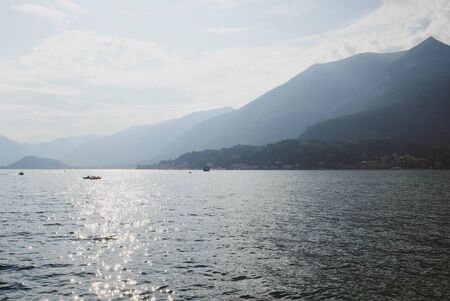 Beautiful mountain landscape with Como Lake or Lago di Como, popular tourist attraction in Lombardy, Northern Italy. Copy space. Summer vacations concept. Water surface with sun glare, evening light.の写真素材