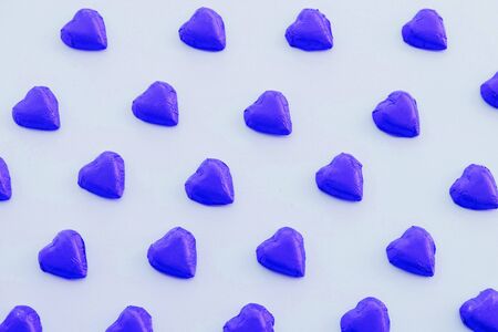Pattern made of blue heart-shaped sweet chocolates on pastel azure background. Valentine's Day card. Love concept.の写真素材