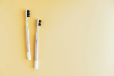 Stylish eco friendly natural bamboo toothbrushes on pastel yellow background.の写真素材