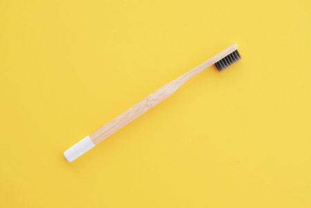 Stylish eco friendly natural bamboo toothbrush on yellow background. Oral hygiene concept. Space for...