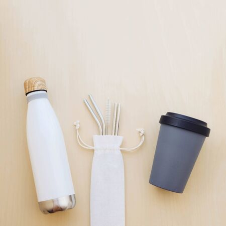 Reusable plastic free and eco friendly utensils. Stylish metal drinking straws and water bottle, bamboo coffee cup, top view. Flat lay. Copy space. Zero waste. Reduce, reuse, recycle.の写真素材