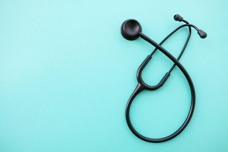 Black stethoscope on light blue background. Medicine and healthcare, cardiology, medical education. Acoustic medical device. Space for text. Flat-lay, top view.の写真素材