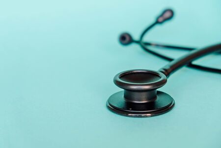 Black stethoscope on light blue background, close up. Medicine and healthcare, cardiology, medical education. Acoustic medical device. Space for text.の写真素材