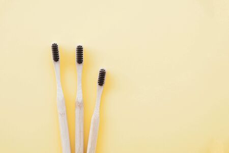 Stylish eco friendly natural bamboo toothbrushes on pastel yellow background. Oral hygiene concept. Space for text. Flat-lay style, top view. Reduce plastic waste, sustainable lifestyle.の写真素材