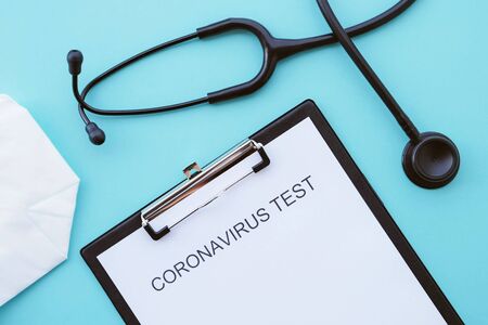 Coronavirus, COVID-19, SARS-CoV-2, 2019-nCoV epidemic concept. Flat lay with medical form, text Coronavirus test, protective, mask and black stethoscope on light blue background, top view.の写真素材