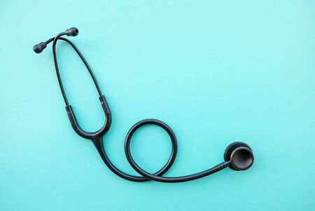 Black modern stethoscope on light blue background. Medicine and healthcare, cardiology, medical education. Acoustic medical device. Space for text. Flat-lay, top view.の写真素材