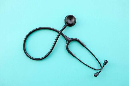 Black modern stethoscope on light blue background. Medicine and healthcare, cardiology, medical education. Acoustic medical device. Space for text. Flat-lay, top view.の写真素材