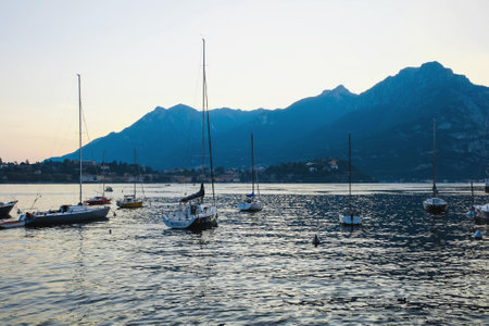 Como, Italy - September 1, 2019: Evening view of Como Lake or Lago di Como with boats in summer. Popular tourist attraction in Lombardy, Northern Italy.のeditorial素材