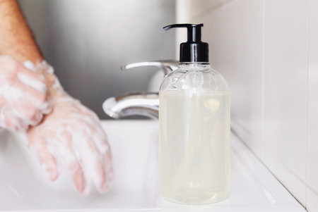 Washing hands concept. Man cleaning his hands using liquid disinfectant soap and water in bathroom,...