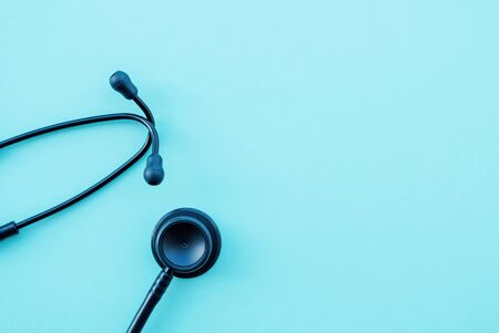 Black modern stethoscope on light blue background, close up. Medicine and healthcare, cardiology, medical education. Acoustic medical device. Space for text. Flat-lay, top view.の写真素材