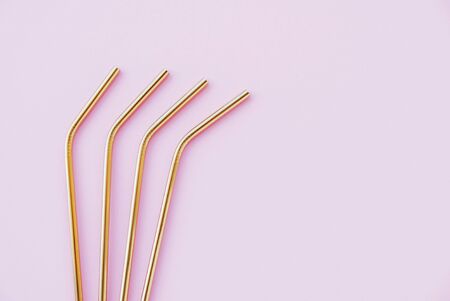 Reusable eco-friendly golden metal straws on pastel pink background.の写真素材