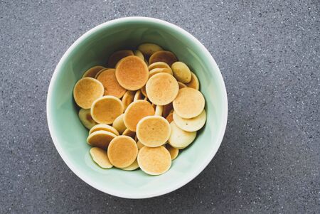 Freshly cooked pancake cereal in a bowl on grey concrete background, top view. Copy space. Mini pancakes. Food for kids. Breakfast ideas.の写真素材