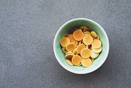 Freshly cooked pancake cereal in a bowl on grey concrete background, top view. Copy space. Mini pancakes. Food for kids. Breakfast ideas.の写真素材
