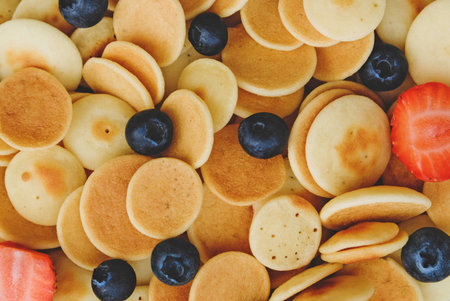 Freshly cooked pancake cereal served with fresh berries, top view, close up. Mini pancakes. Food for...
