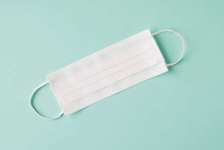 Protective facial mask on pastel green background, top view. Copy space. Personal hygiene, health care and Coronavirus Covid-19 prevention.の写真素材