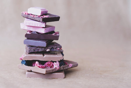 Stack of dark, milk, pink chocolate and chocolate with fruits and nuts.