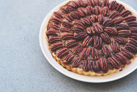Delicious freshly baked homemade pecan pie on gray concrete background. Copy space. Popular holiday meal for Thanksgiving and Christmas.の写真素材