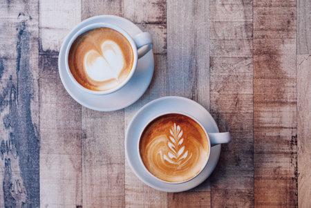 Two cups of fresh delicious cappuccino coffee with beautiful latte art on wooden background. From above, copy space.の写真素材