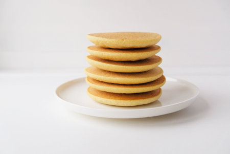 Freshly cooked soft delicious gluten free pancakes stacked on white plate, close up. Space for text. Healthy sweet food.の写真素材