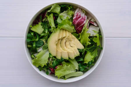 Green mix salad in a bowl on white wooden background.の写真素材