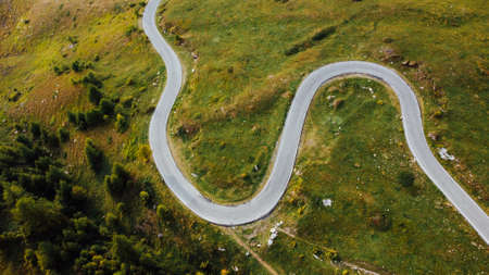 Aerial view of narrow road among green summer field in the mountains.の写真素材