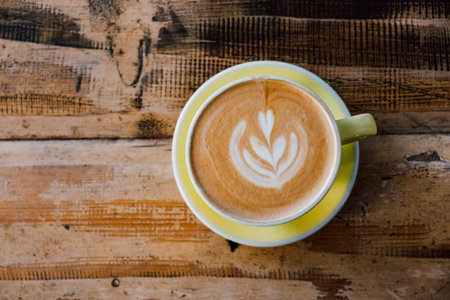 Cup of fresh delicious cappuccino coffee with beautiful latte art in the shape of leaf on shabby...