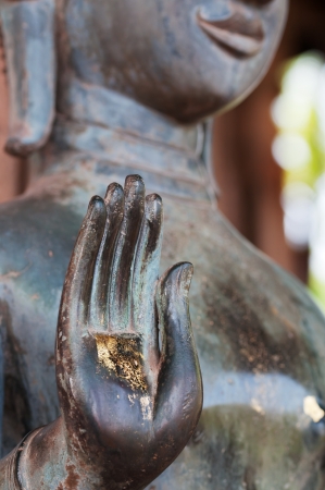 Spiritual concept with Standing bronze Buddha statue with open gold palmの写真素材