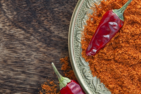 Oriental copper plate with dried crushed chili red pepper powder and whole dried chili peppers on dark wood background  Oriental spicy food concept の写真素材