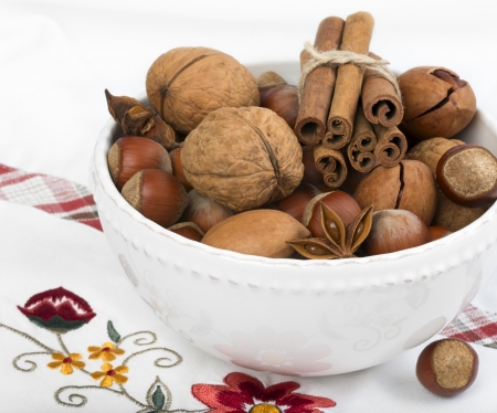 Anise, cinnamon and variety of nuts in the bowl on the white tableclothの写真素材
