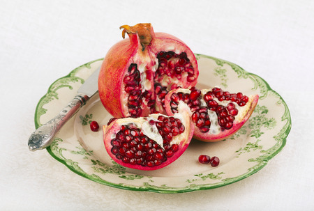 Opened red pomegranate on a rustic plateの写真素材