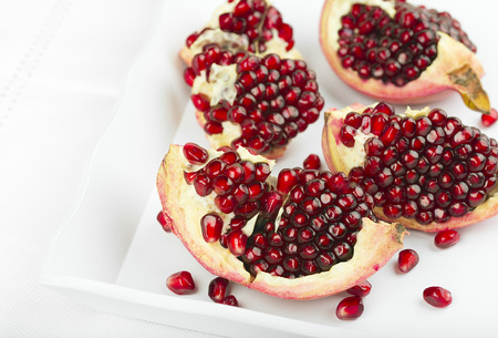Red pomegranate on a white trayの写真素材