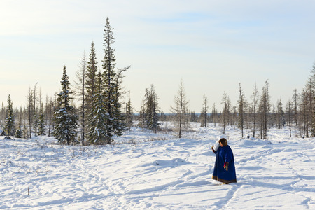 Woman of indigenous tribe of Polar Circle bears piece of snow to melt it for preparation of tea.の写真素材