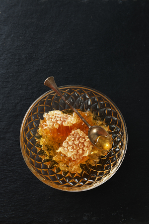 Honey, spoon and honeycomb on a black stone table backgroundの写真素材
