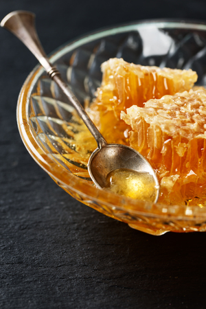 Honey, spoon and honeycomb on a black stone table backgroundの写真素材