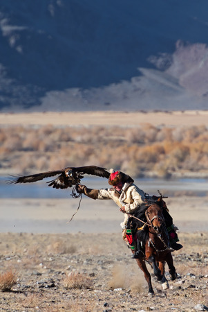 Bayan-Olgii, Mongolia - October 06, 2018: Unknown huntsman with golden eagle shows his experience in falconry.のeditorial素材