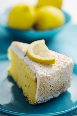 slice of lemon pie with lemons in the background, focus is on the front of the cakeの写真素材