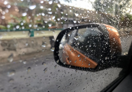 Rain drop on the cars side window. Reflex image from the mirror.
