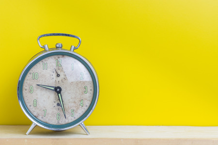 Old alarm clock on the yellow wall.の写真素材