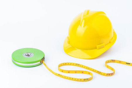Yellow safety helmet and green measuring tape on white backgroundの写真素材