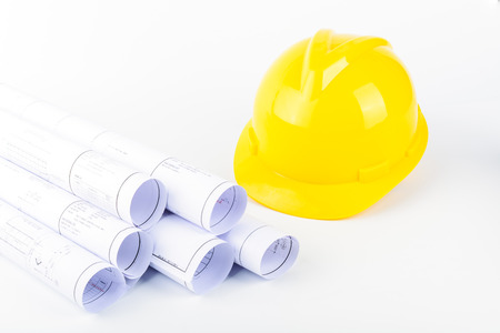Yellow safety helmet and Scrolls of engineering drawings.の写真素材