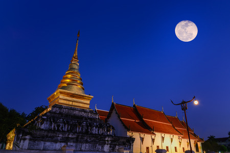 Moon on night sky over Wat Phrathat Chang Kham Worawihan in twilight scene with light trails from long exposure.のeditorial素材