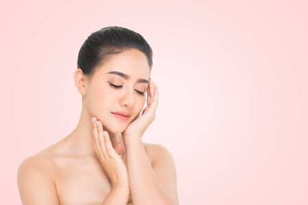 Beautiful Young Woman with clean fresh skin, Proposing a product. Gestures for advertisement on beige backgroundの写真素材